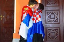 Poljubac mladića i djevojke ogrnute u srpsku i hrvatsku zastavu