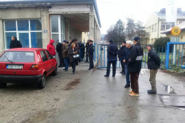 Kroz kapiju gledaju tvornicu koju su izgradili